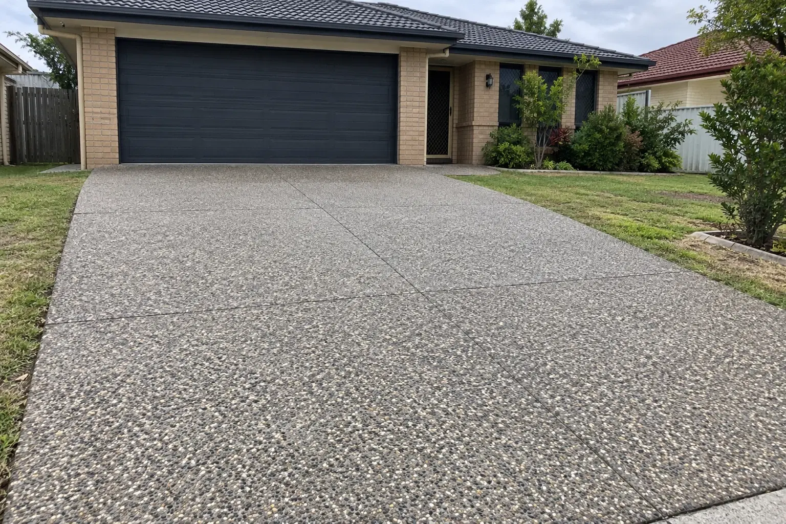 Design concept of a grey exposed aggregate driveway at a Brisbane-style brick home