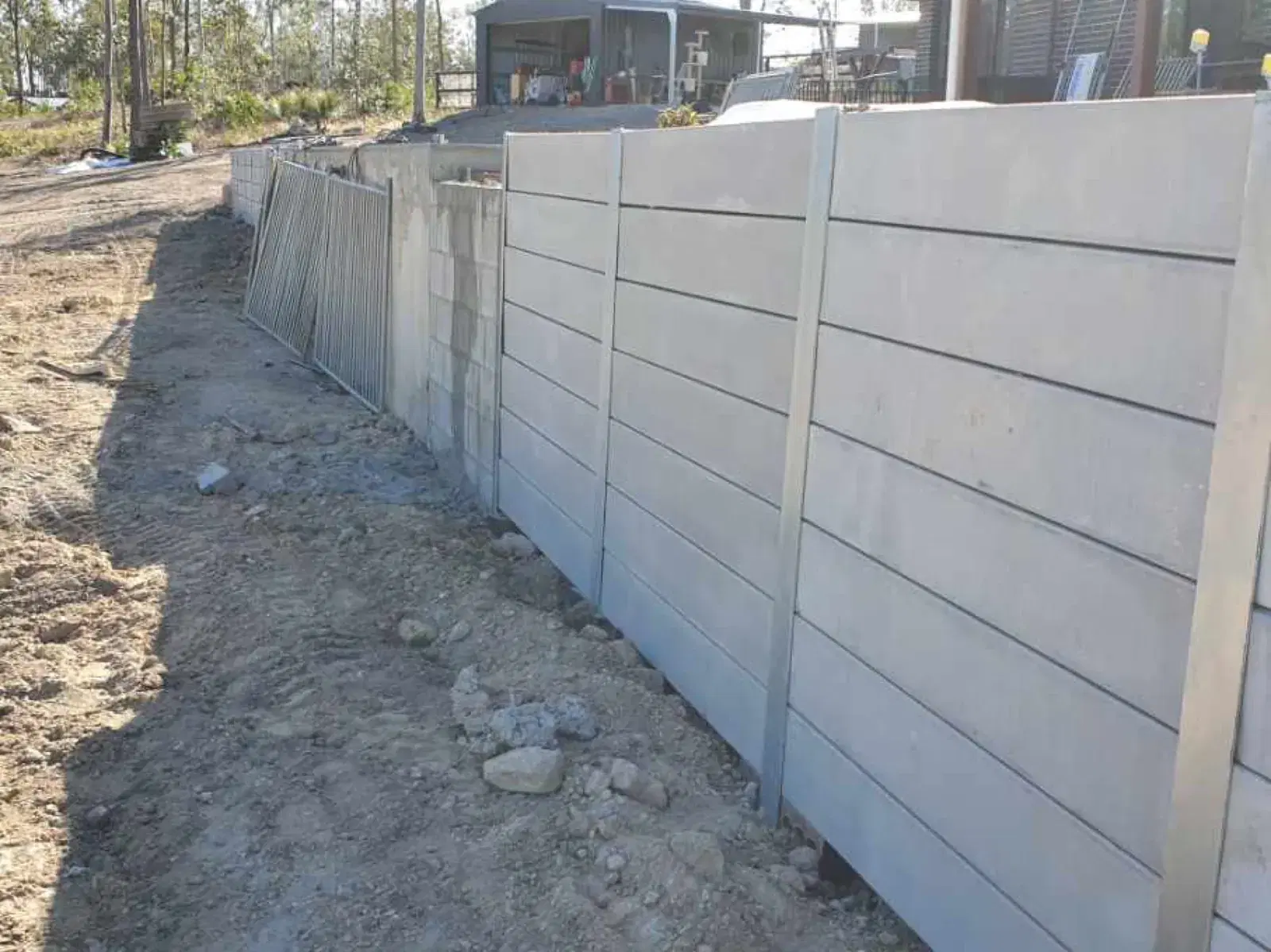 Light concrete sleeper retaining wall installed beside a residential yard