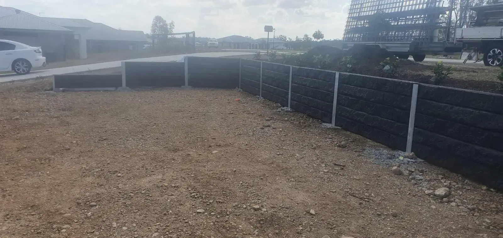 Dark concrete sleeper retaining wall around a prepared building site