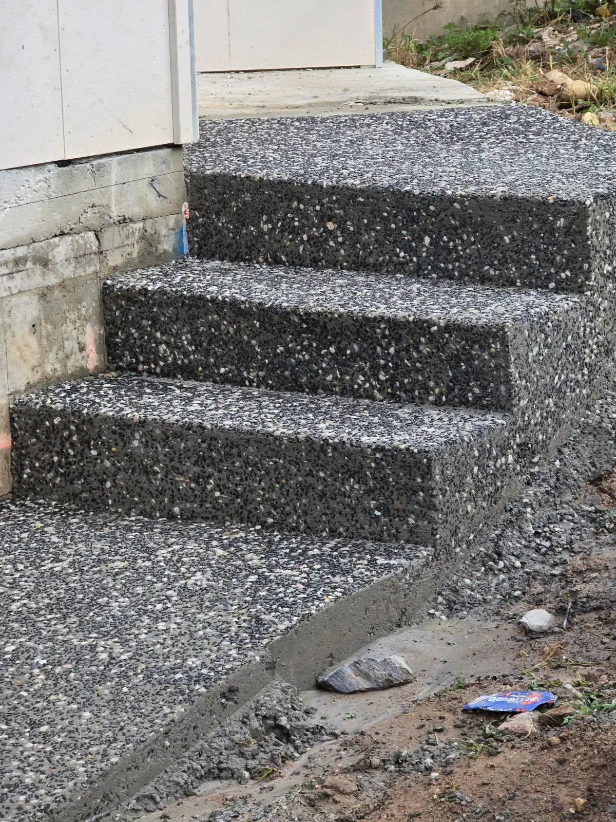 Exposed aggregate concrete entry steps and landing beside a home