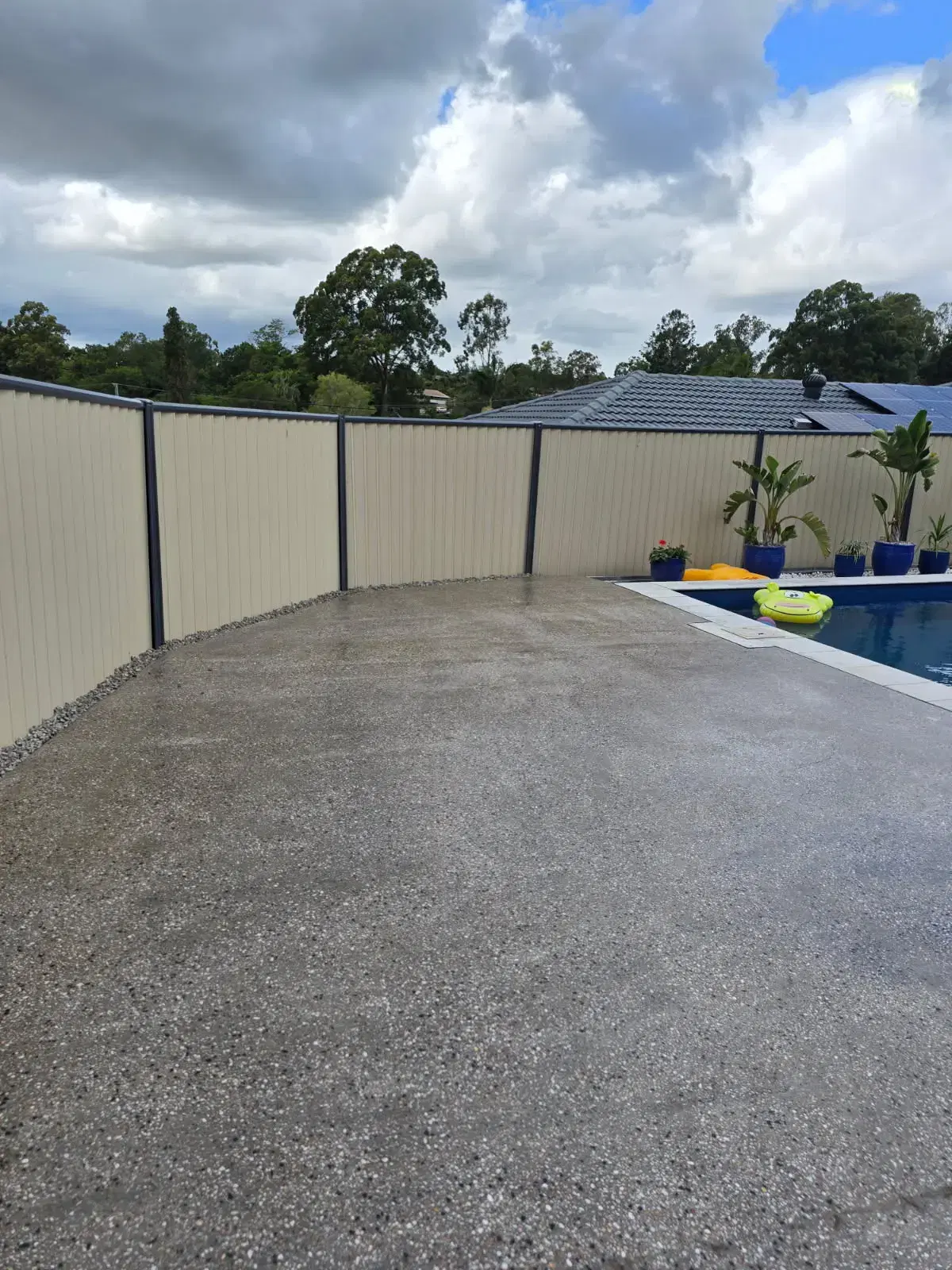 Exposed aggregate concrete pool surround with wide outdoor entertaining area and pool edge