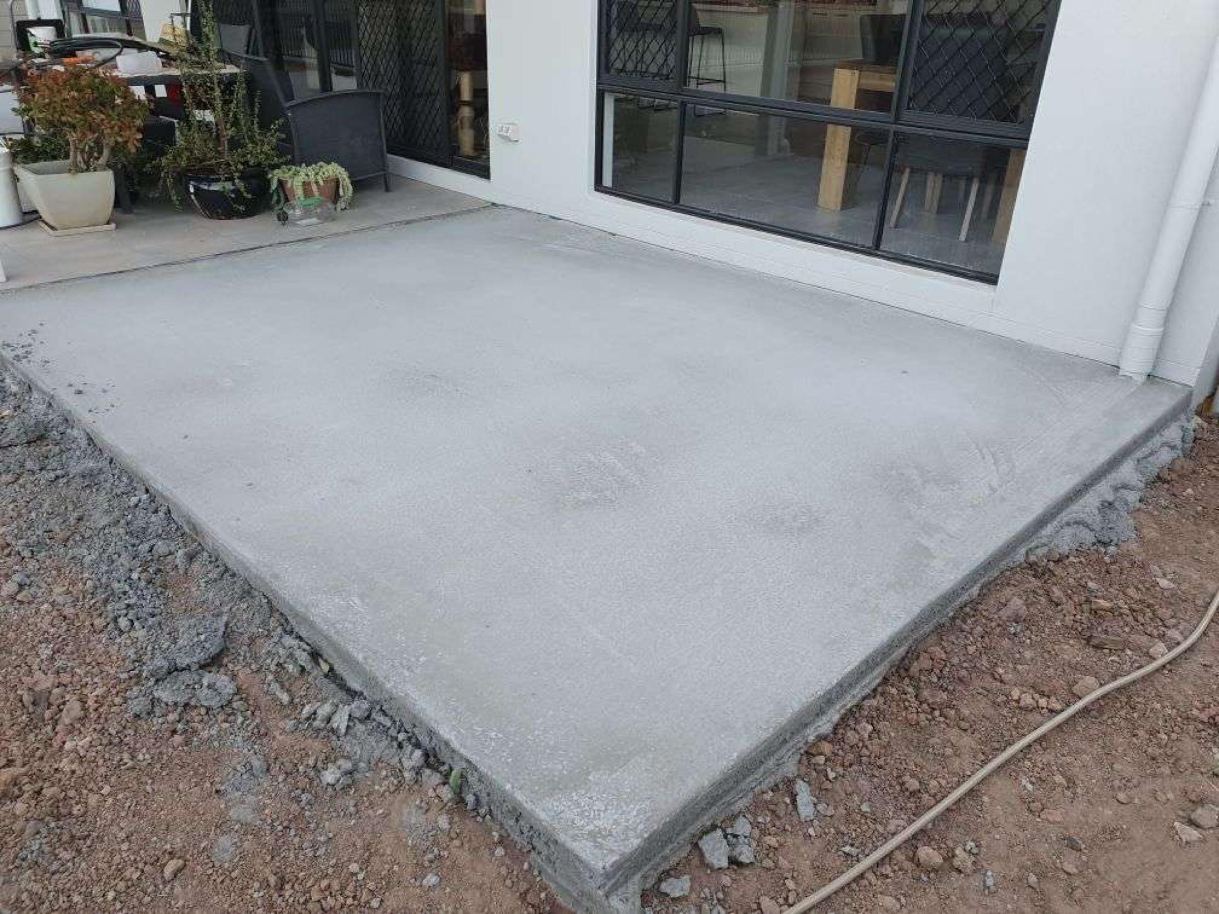 Freshly poured concrete patio slab beside a home