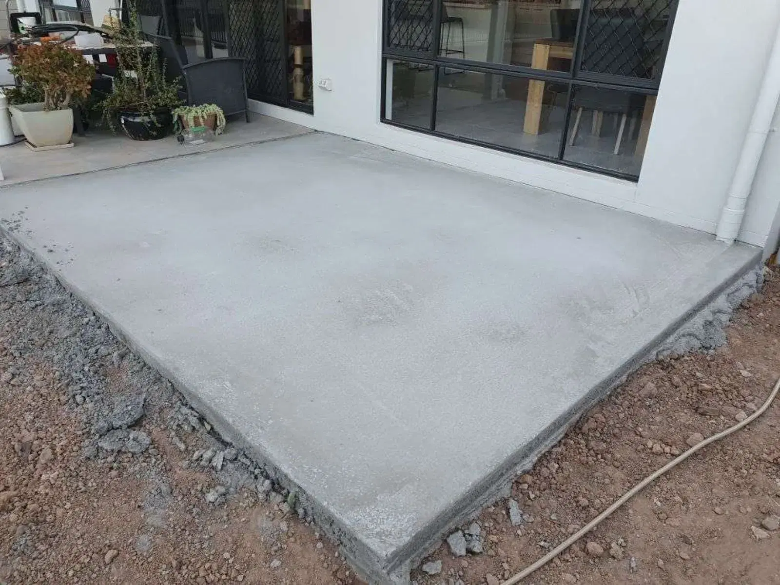 Fresh concrete patio slab poured beside a residential home