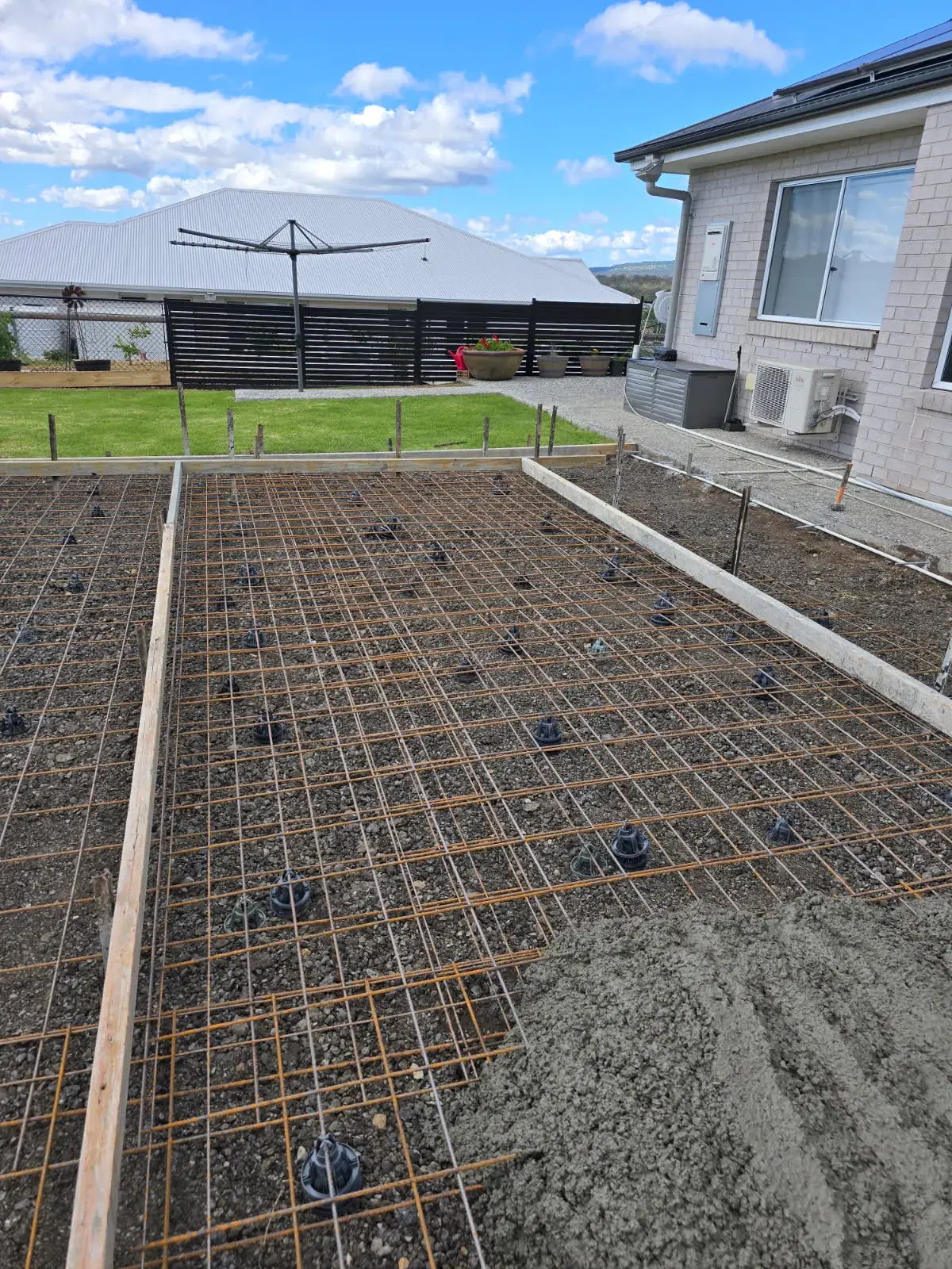 Concrete slab reinforcement and formwork prepared beside a residential home