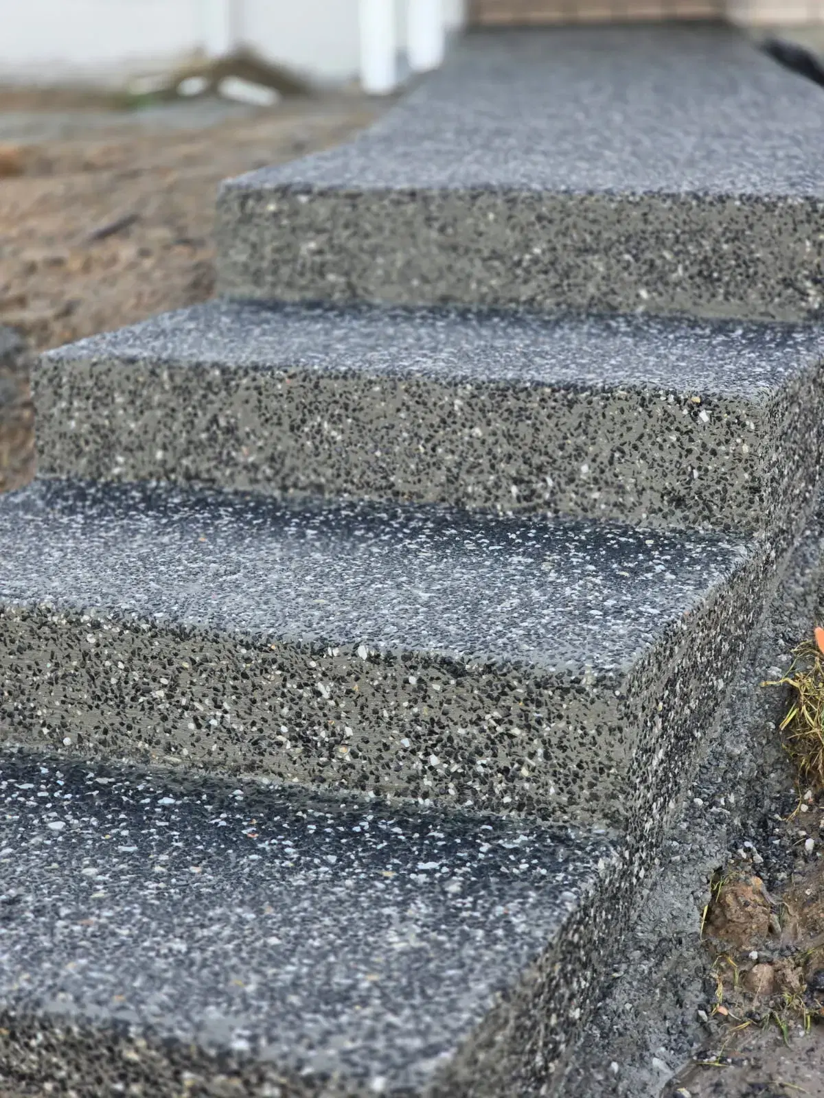 Close-up of exposed aggregate concrete steps with dark stone finish