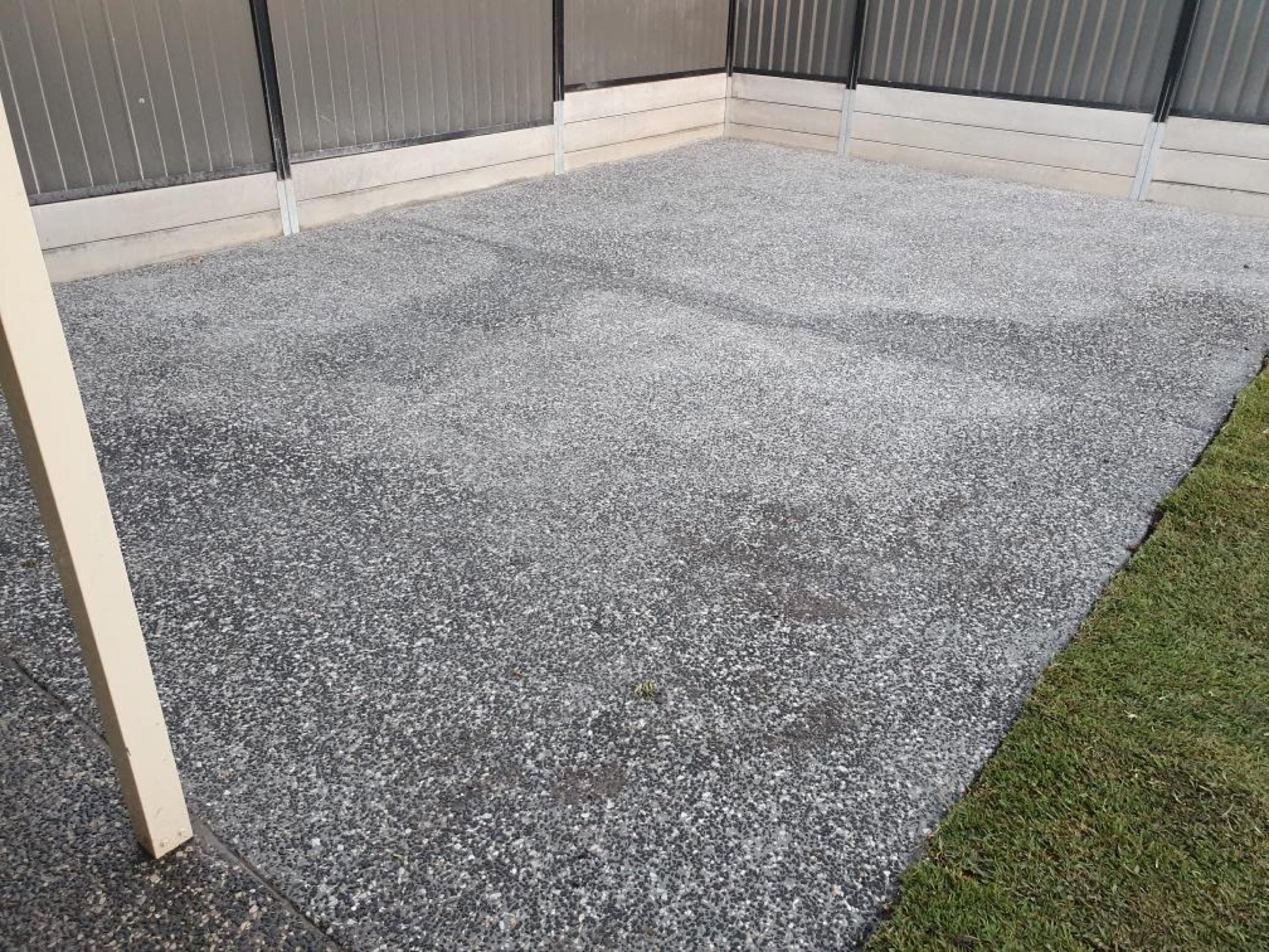 Grey exposed aggregate patio beside a lawn