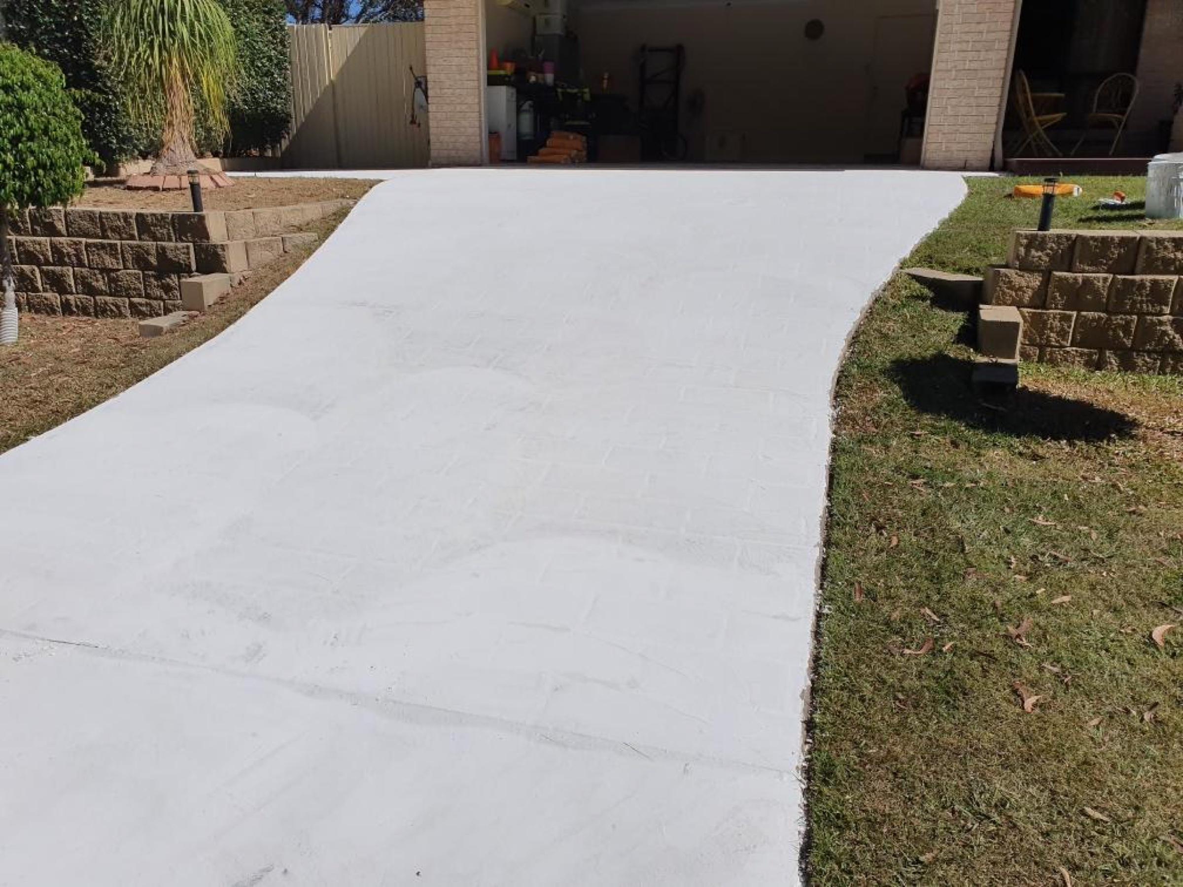 Fresh plain concrete driveway leading to a residential garage