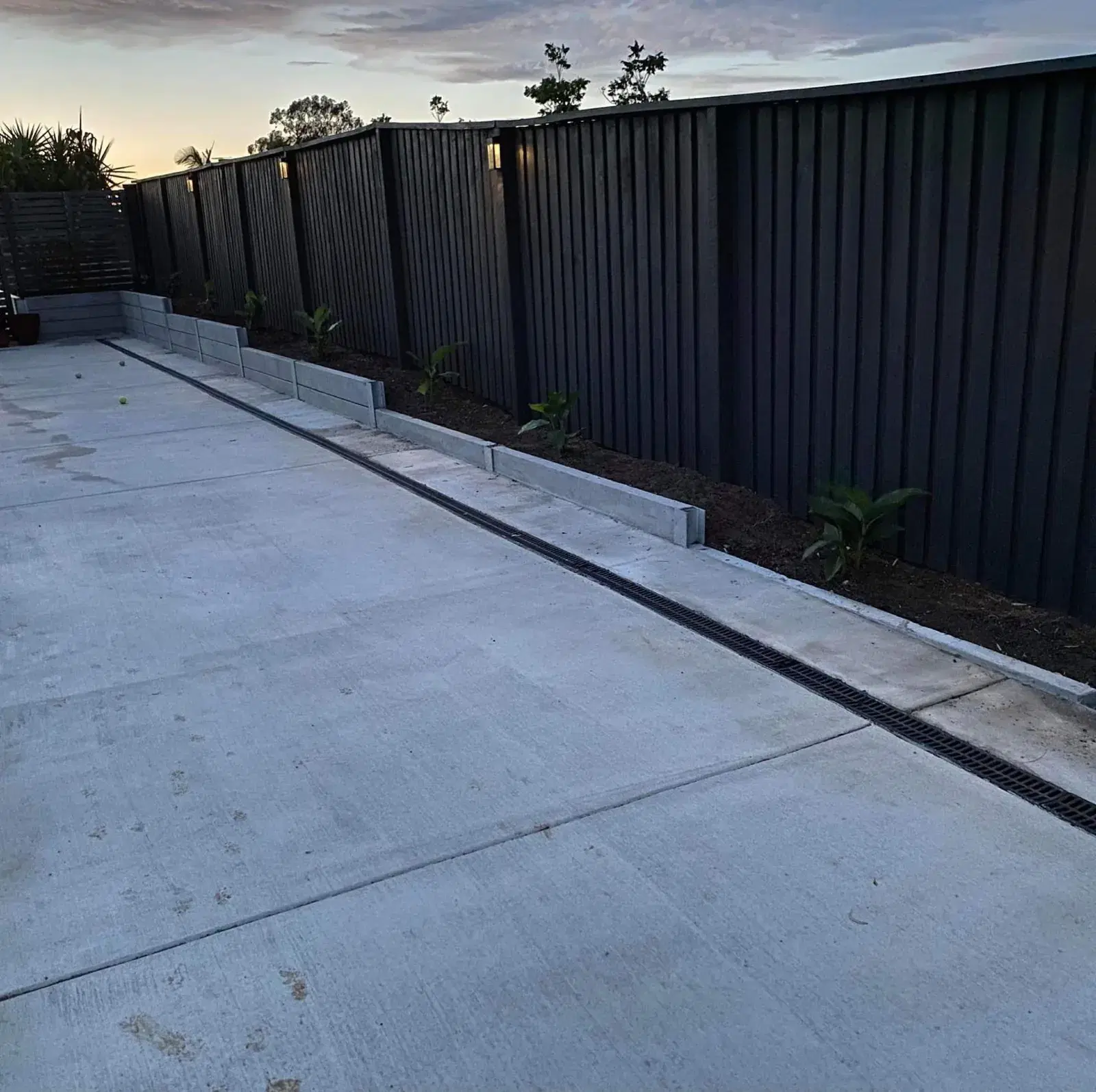 Plain concrete side access path with channel drainage beside a home